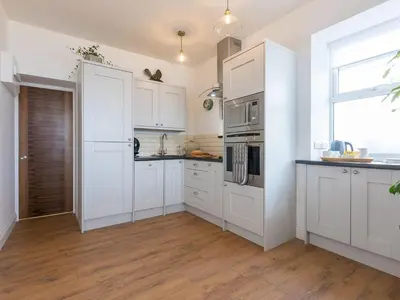a white kitchen with white cabinets and a window at Hepworth Apartment in St Ives