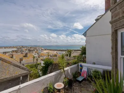 a balcony with a view of a city and the ocean at Hepworth Apartment in St Ives