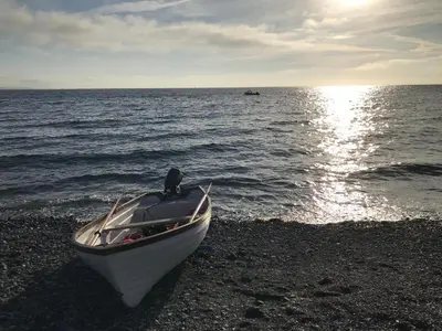 a boat sitting on a beach next to the water at The Old Stable in Helston