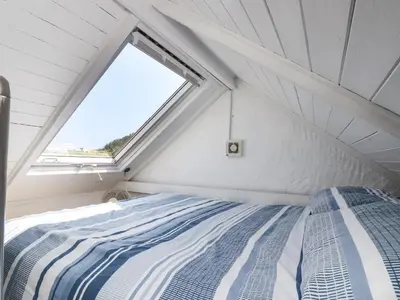 a bed in a small room with a window at The Old Stable in Helston