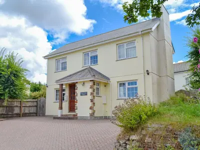 a large white house with a brick driveway at Poppy Cottage in Crantock
