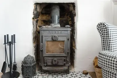 an old wood stove in a room with a chair at No3 Gweek in Gweek