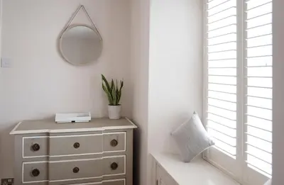 a white bedroom with a dresser and a mirror at No3 Gweek in Gweek
