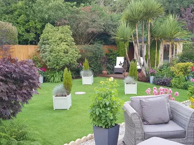 a garden with chairs and potted plants and trees at Eden's Rest Bed and Breakfast in St Austell