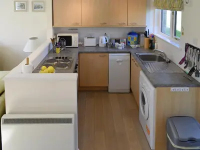 a kitchen with a sink and a washing machine at Hazel Cottage in Budock Water
