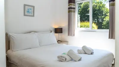 a bedroom with a white bed with towels on it at Ta Mill Cottages & Lodges - Meadowview Chalet 2 in Launceston