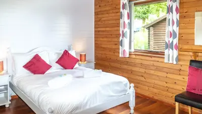 a bedroom with a white bed with red pillows at Ta Mill Cottages & Lodges - Brookview Lodge 1 in Launceston