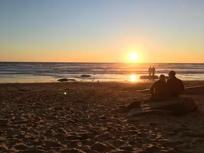 a group of people sitting on the beach watching the sunset at Shepherds hut with valley views in Bodmin