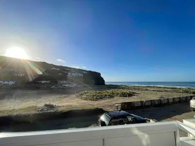 a car parked on the beach near the ocean at Whispering Waves in Porthtowan, Beachfront Apartment in Porthtowan