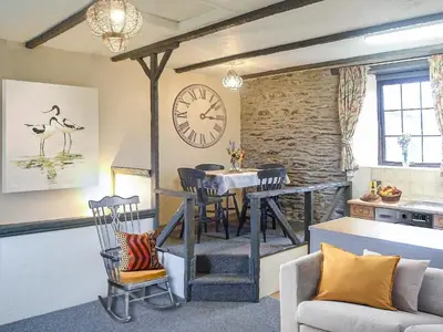a living room with a table and a clock on the wall at Sage Cottage in Truro