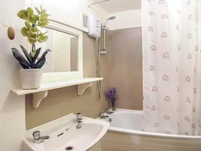 a bathroom with a sink and a shower curtain at Sage Cottage in Truro