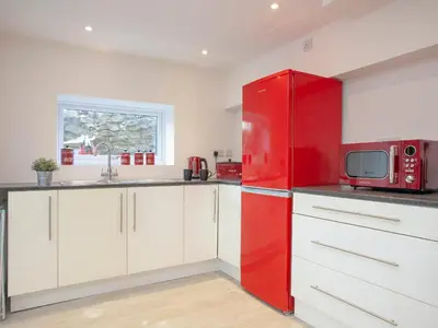 a red refrigerator in a kitchen with white cabinets at Crofty's Celder - Uk35181 in Pool