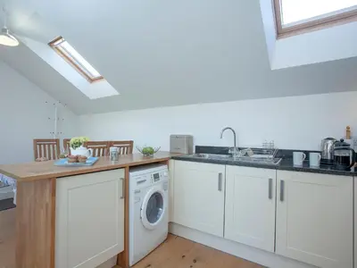 a kitchen with white cabinets and a washing machine at The Hayloft - Uk36516 in Germoe