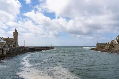 a body of water next to a pier with a clock tower at Finest Retreats - The Hideaway - Studio Apartment in Porthleven in Porthleven