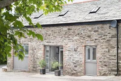 a stone cottage with two garage doors and two potted plants at St Tudy Inn in Bodmin