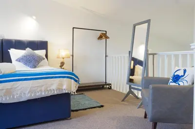 a bedroom with a bed and a mirror and a chair at Coverack in Budock Water