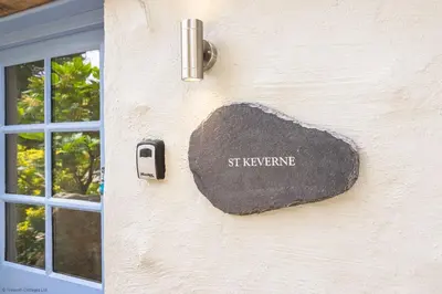 a stone sign on the side of a building with a window at St Keverne in Budock Water