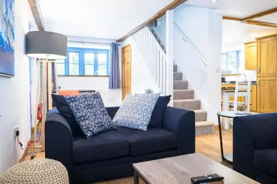 a living room with a blue couch and stairs at St Keverne in Budock Water