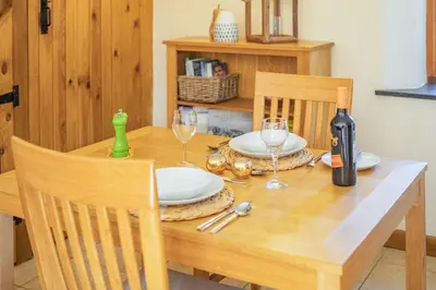a dining room table with a bottle of wine and glasses at Miller's Lodge in Liskeard