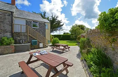 a picnic table and benches in front of a house at The Laurels Holiday Park & Cottages nr Padstow and Wadebridge in Wadebridge