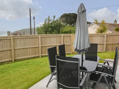 a table with an umbrella and chairs in a backyard at 3 Praa Cove in Penzance