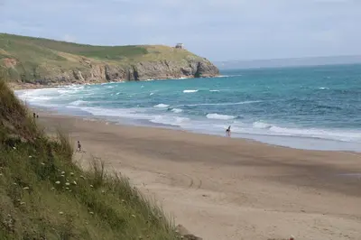 a beach with people walking on the sand and the ocean at 3 Praa Cove in Penzance