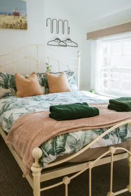 a bedroom with a bed with green sheets and a window at The Old Pirates Lookout in Falmouth