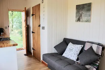 a living room with a gray couch in front of a door at Hare's Hut in Saint Clement