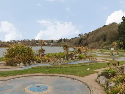 a park with a pond and trees and a body of water at Maple in Falmouth
