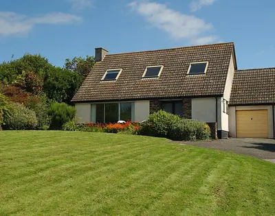 a house with a large green lawn in front of it at Rosevallen in Polzeath