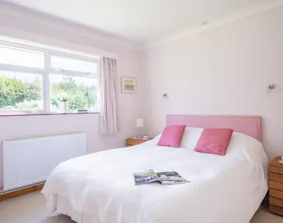 a bedroom with a large white bed with pink pillows at Rosevallen in Polzeath