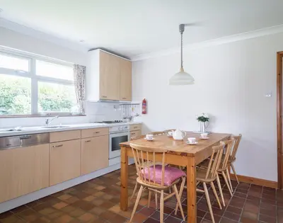 a kitchen with a wooden table and some chairs at Rosevallen in Polzeath