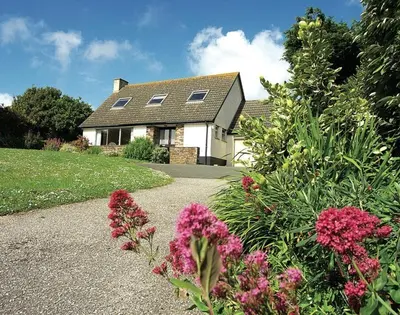 a house with a garden with flowers in front of it at Rosevallen in Polzeath