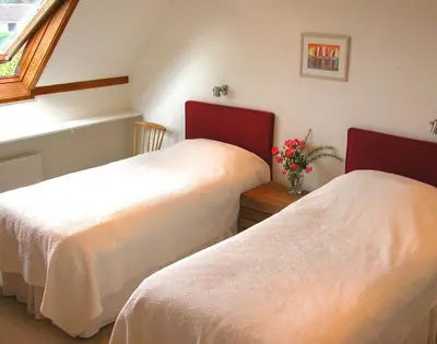 a bedroom with two beds and a vase of flowers on a table at Rosevallen in Polzeath