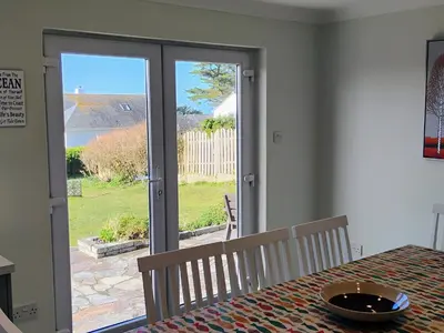 a dining room with a table and a view of a patio at Chy-An-Var in Polzeath