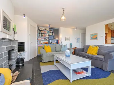 a living room with couches and a fireplace at Upper Gren in Polzeath