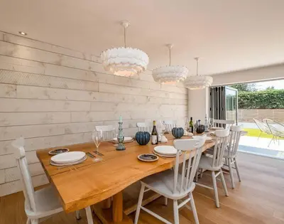 a dining room with a wooden table and white chairs at Seastar in Wadebridge