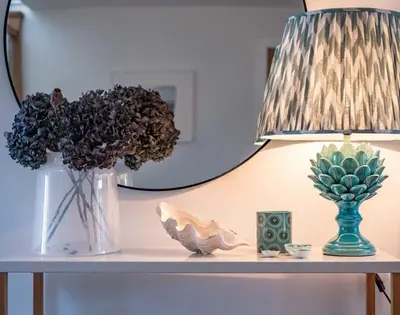 a table with a lamp and a vase with flowers at Seastar in Wadebridge