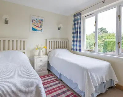 two beds in a bedroom with a window at Ragleighs in Polzeath
