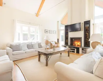 a living room with white furniture and a fireplace at Ragleighs in Polzeath
