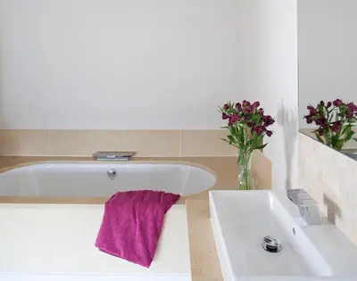 a bathroom with a white tub and a vase of flowers at Downalong in Polzeath