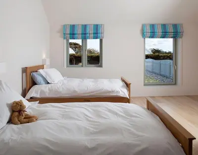 a teddy bear sitting on a bed in a bedroom at Downalong in Polzeath