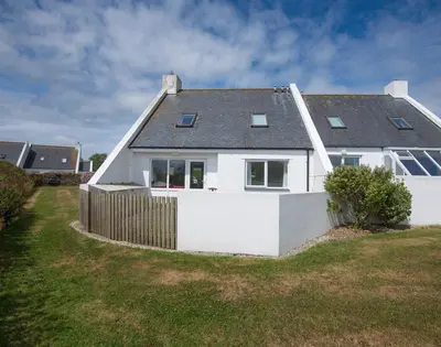 a white house with a fence in a yard at Kirra in Polzeath