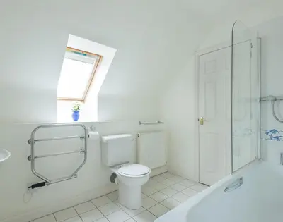 a white bathroom with a toilet and a shower at Kirra in Polzeath
