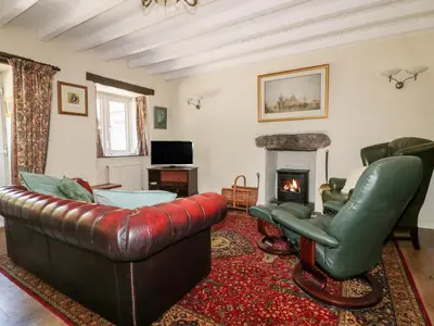 a living room with a leather couch and chairs and a fireplace at Little Trespettigue in Launceston