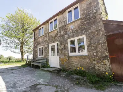 a stone house with a bench in front of it at Little Trespettigue in Launceston