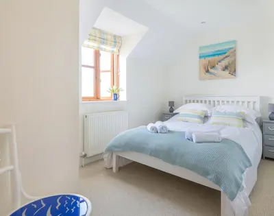 a white bedroom with a bed with towels on it at Lundy Cottage in Saint Minver