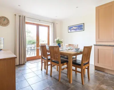 a dining room with a table and chairs in a kitchen at Lundy Cottage in Saint Minver