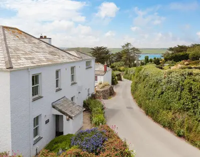 a white house on a road next to a house at Worthy House in Polzeath