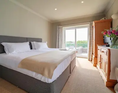 a bedroom with a large bed and a large window at Worthy House in Polzeath
